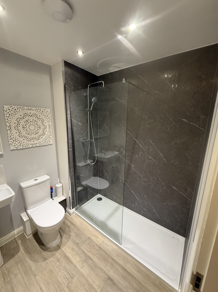 Modern walk-in shower with dark marble-effect wall panels, level-access tray and slim glass screen